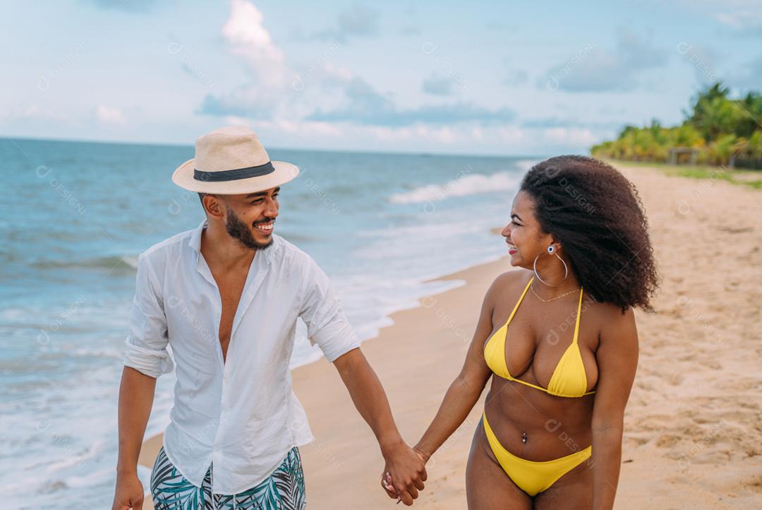 Jovem casal apaixonado na praia, férias de verão, feliz e sorrindo de mãos dadas