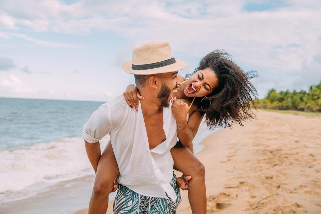 Jovem casal apaixonado na praia, férias de verão, feliz e sorrindo de mãos dadas