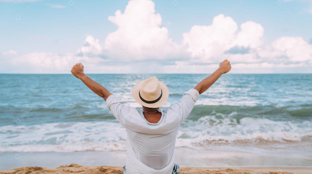 Silhueta de um jovem na praia. homem latino-americano sentado na areia da praia, usando um chapéu o