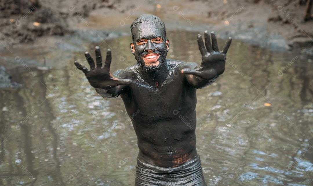 Sorridente jovem latino-americano fazendo tratamento de argila verde. foco no rosto