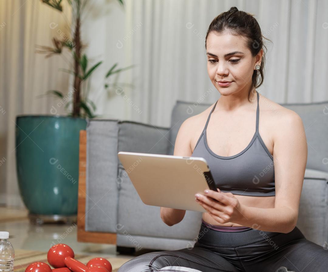 Atraente jovem latina exercitando online em casa.