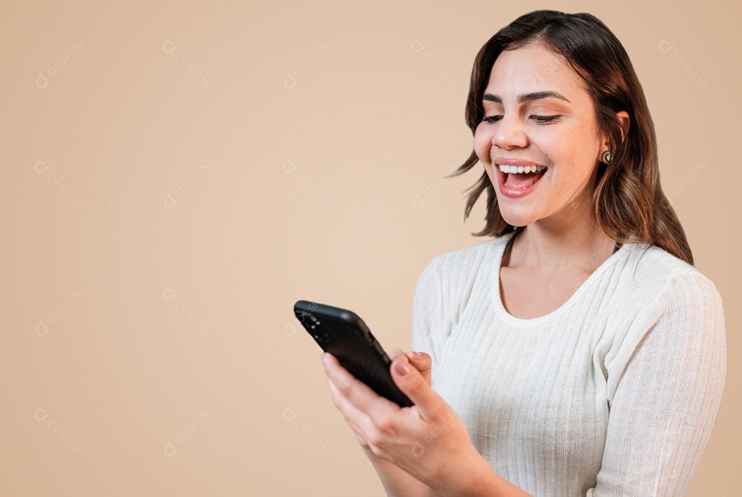 Muito jovem mulher latina usando smartphone em pé no fundo pastel bege isolado se sentindo feliz.