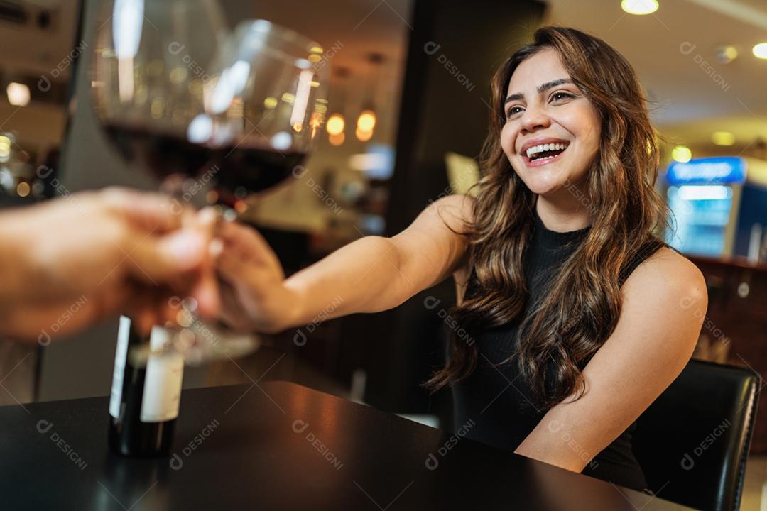 Lindo casal jovem latino com taças de vinho tinto no restaurante