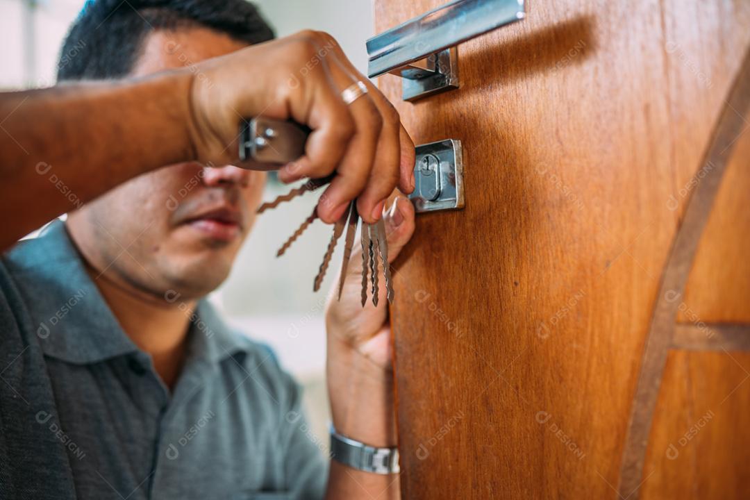 Serralheiro abrindo uma porta. Close-up de mãos masculinas reparando ou instalando uma fechadura de porta de metal