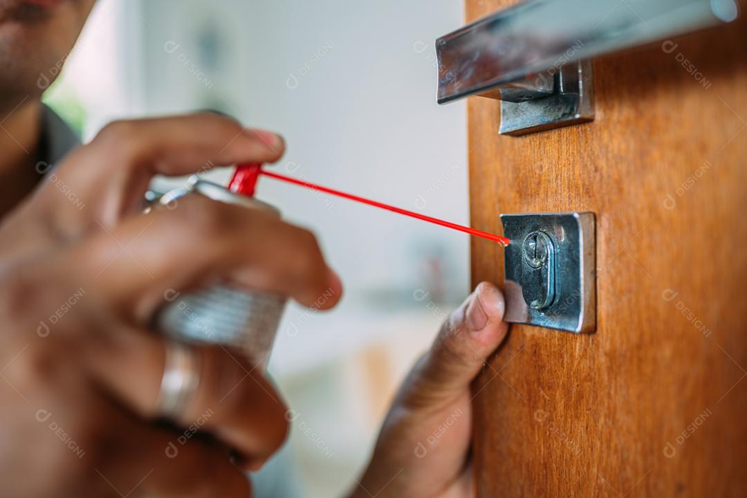 Serralheiro abrindo uma porta. Aplicação de spray antioxidante