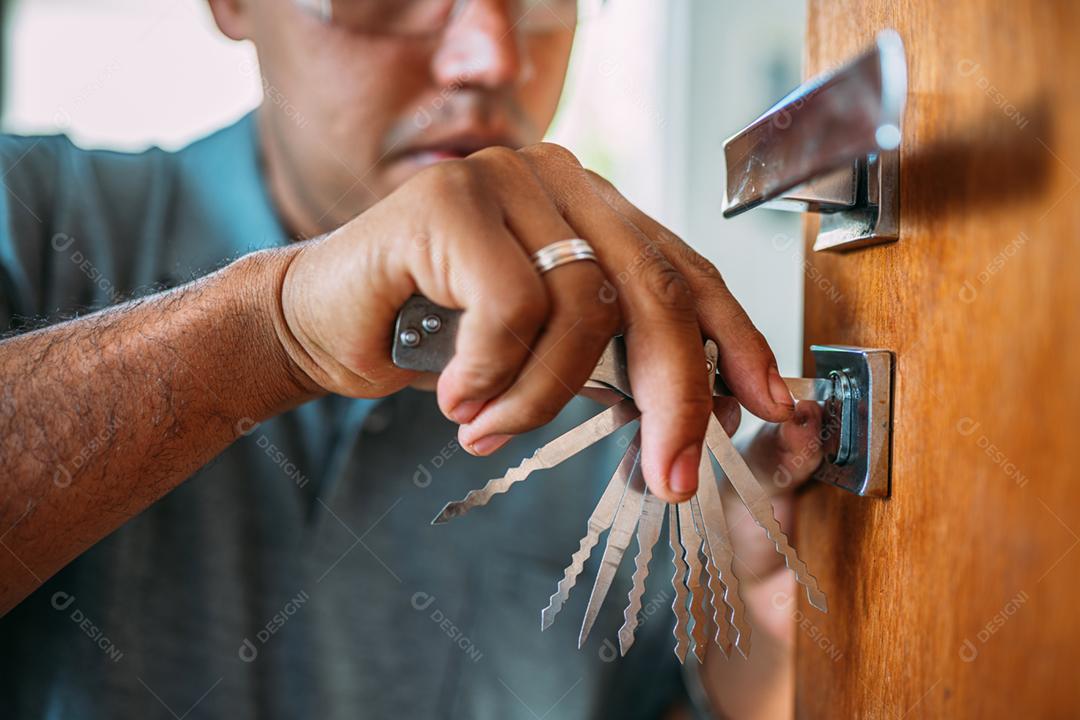 Serralheiro abrindo uma porta. Close-up de mãos masculinas reparando ou instalando uma fechadura de porta de metal