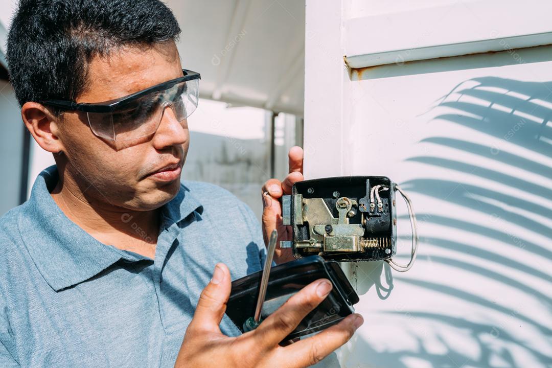 Close-up de mãos masculinas reparando ou instalando uma fechadura eletrônica de metal.