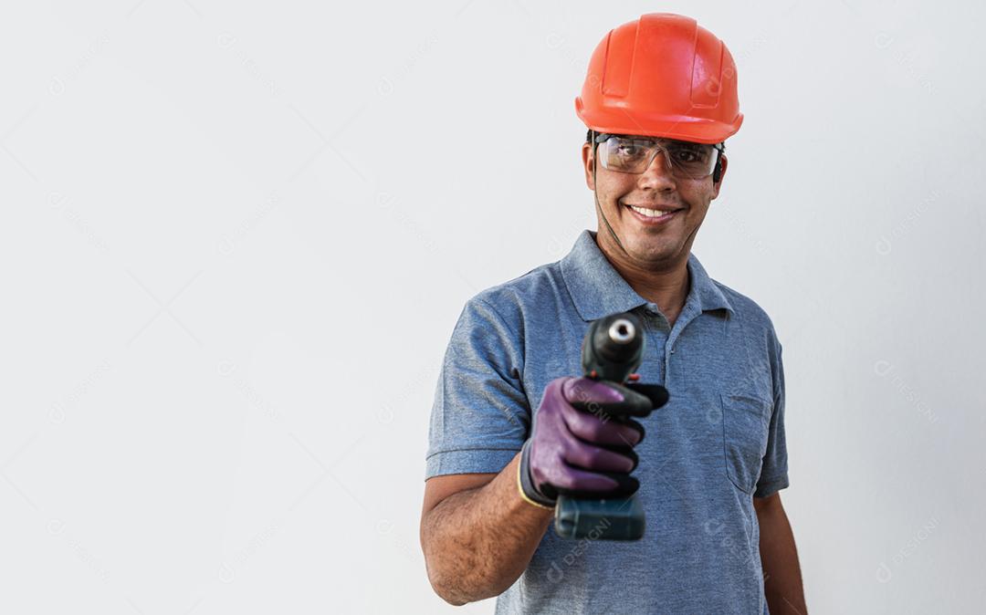 Confiante jovem carpinteiro latino masculino no capacete de segurança segurando broca e olhando para a câmera