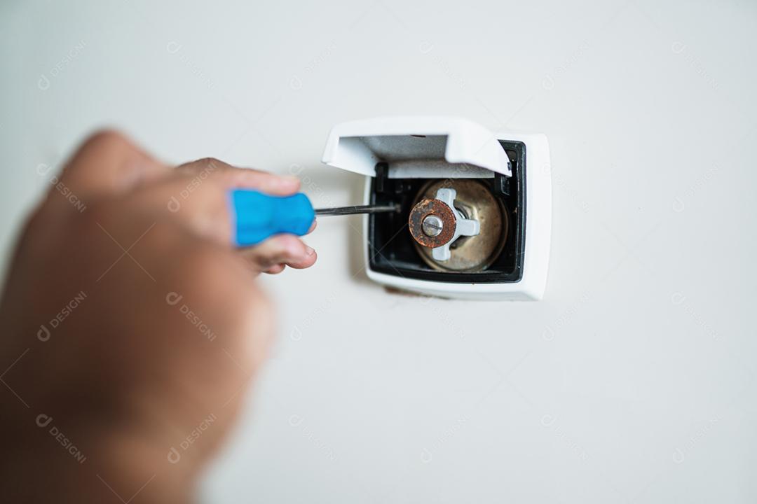 Encanador reparando o botão de descarga no banheiro da casa.