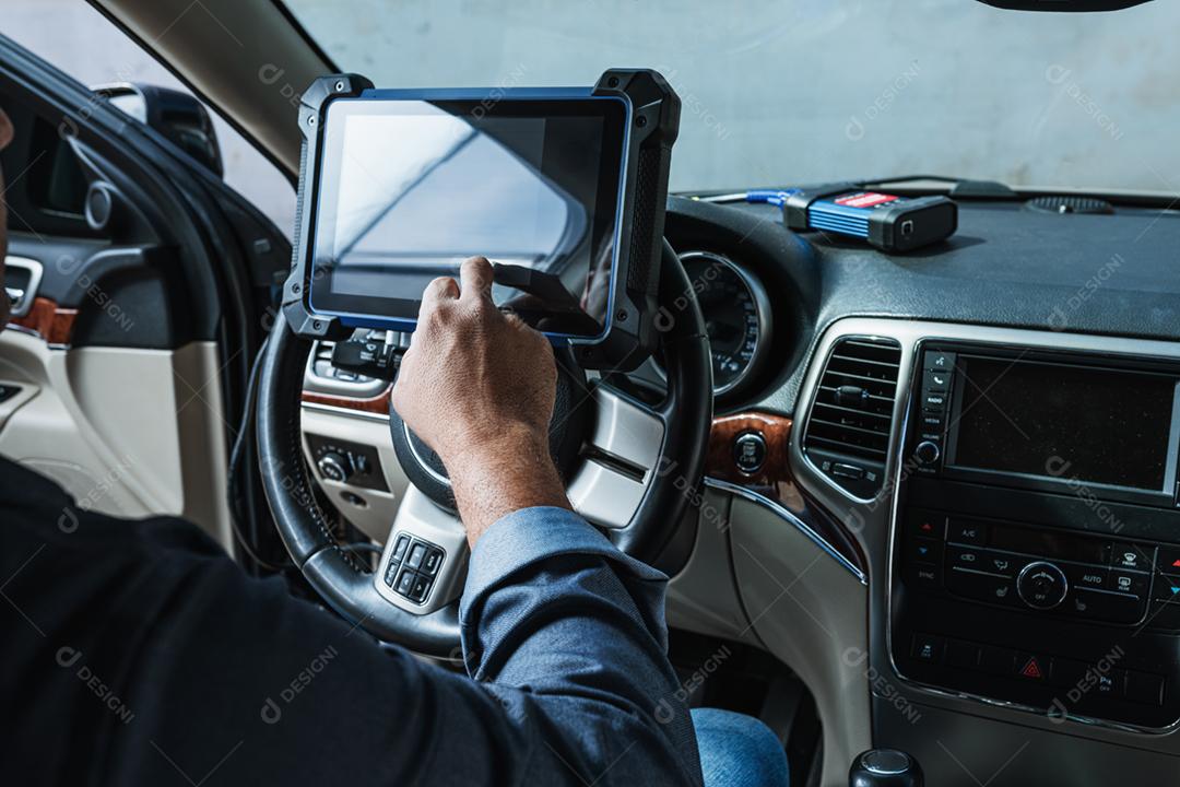 Diagnóstico do carro. Inspeção técnica, eletrônica do carro. Um homem latino segura um dispositivo de digitalização.