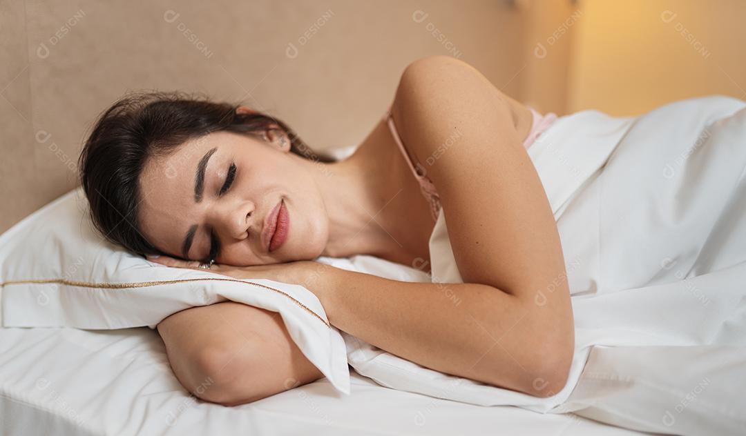 Mulher deitada dormindo contente, bom descanso em cama confortável