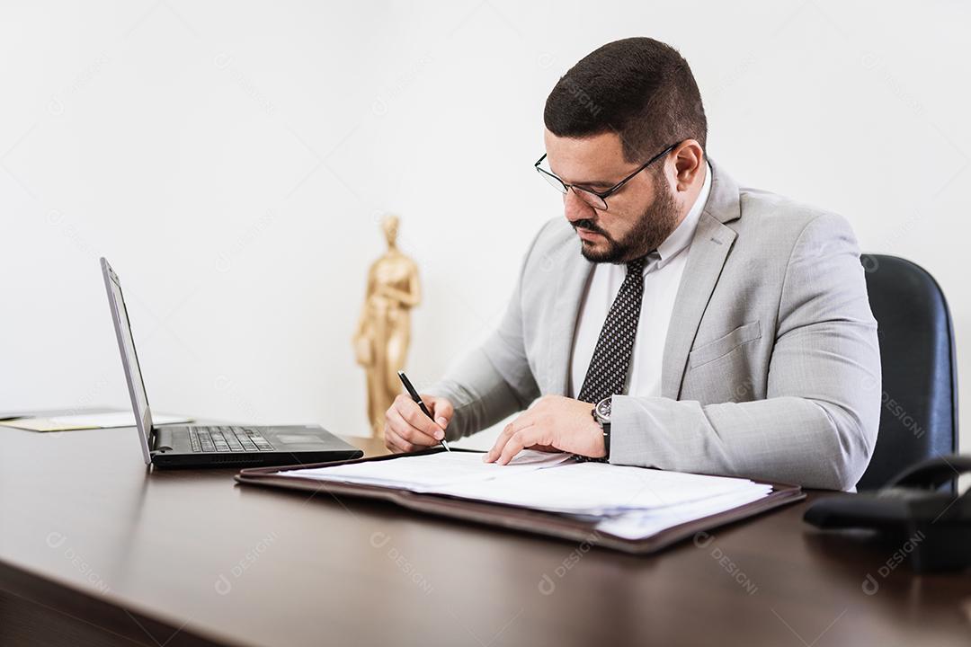 Empresário trabalhando no escritório com laptop e documentos em sua mesa