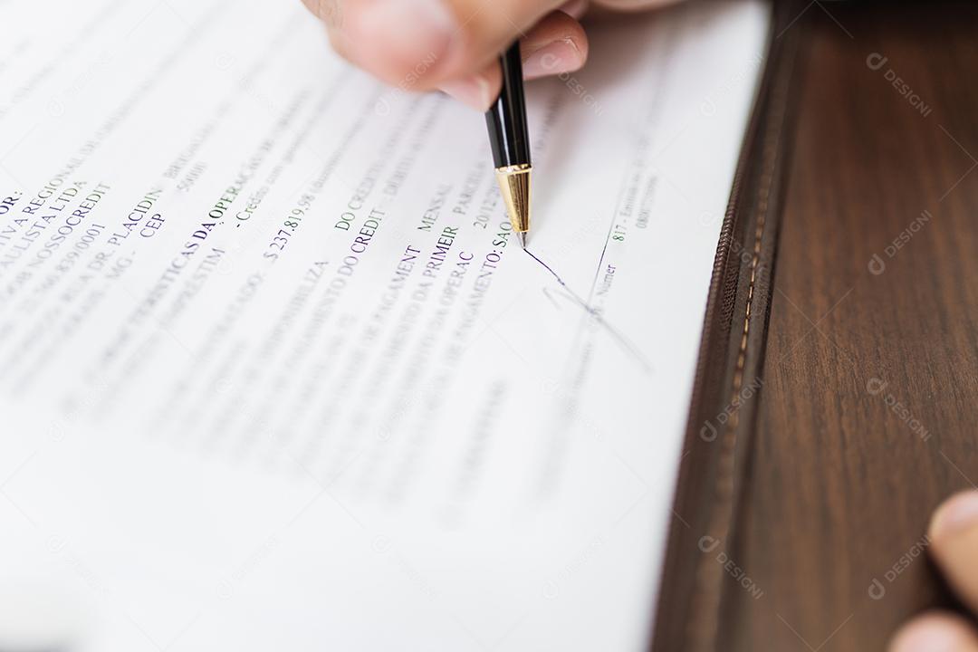 Homem de empresário assina documentos com uma caneta fazendo a assinatura