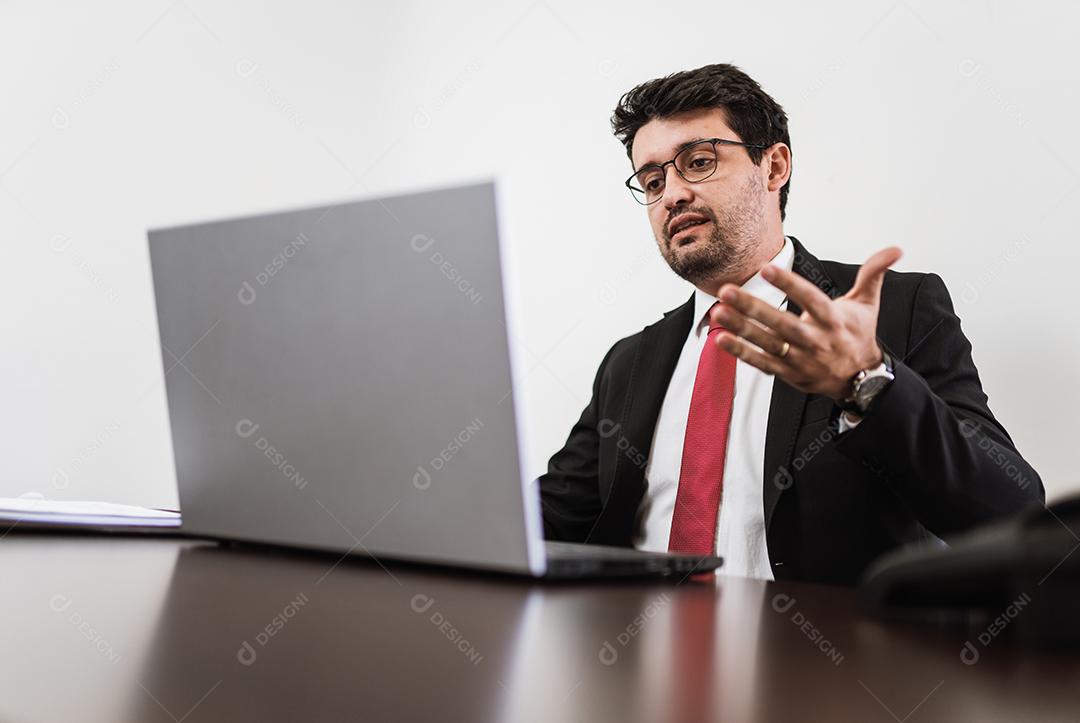 Empresário em videoconferência com laptop e documentos