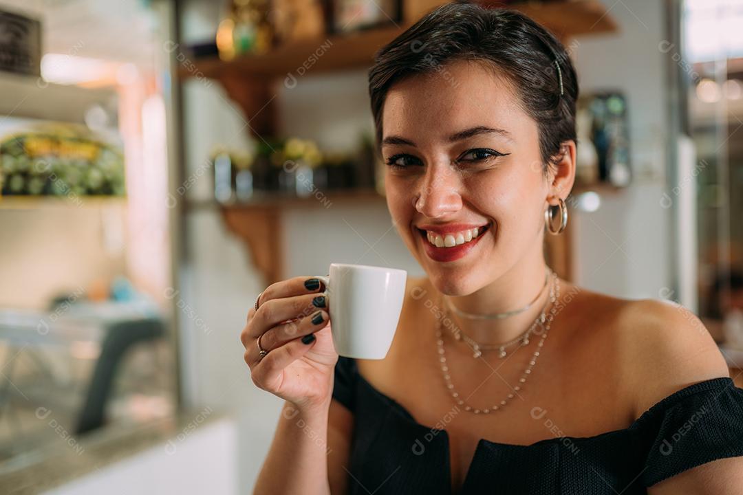 Jovem linda mulher latina feliz desfrutando café em uma rua