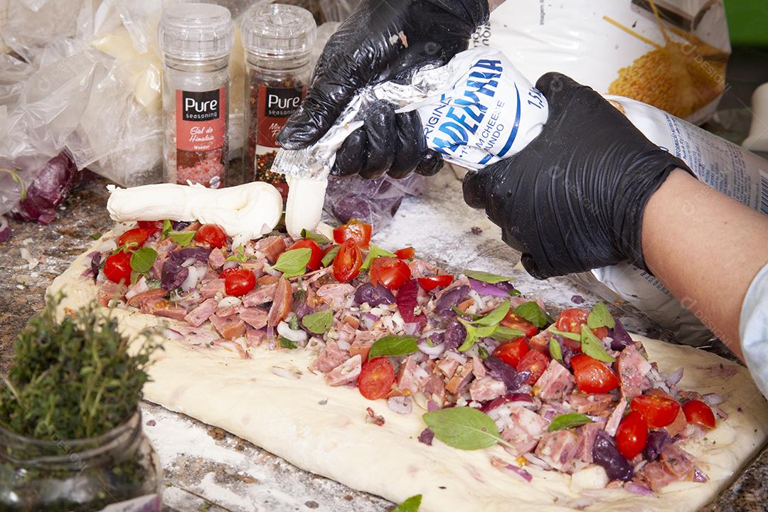 Pessoa botando recheio na pizza comida pizzarias