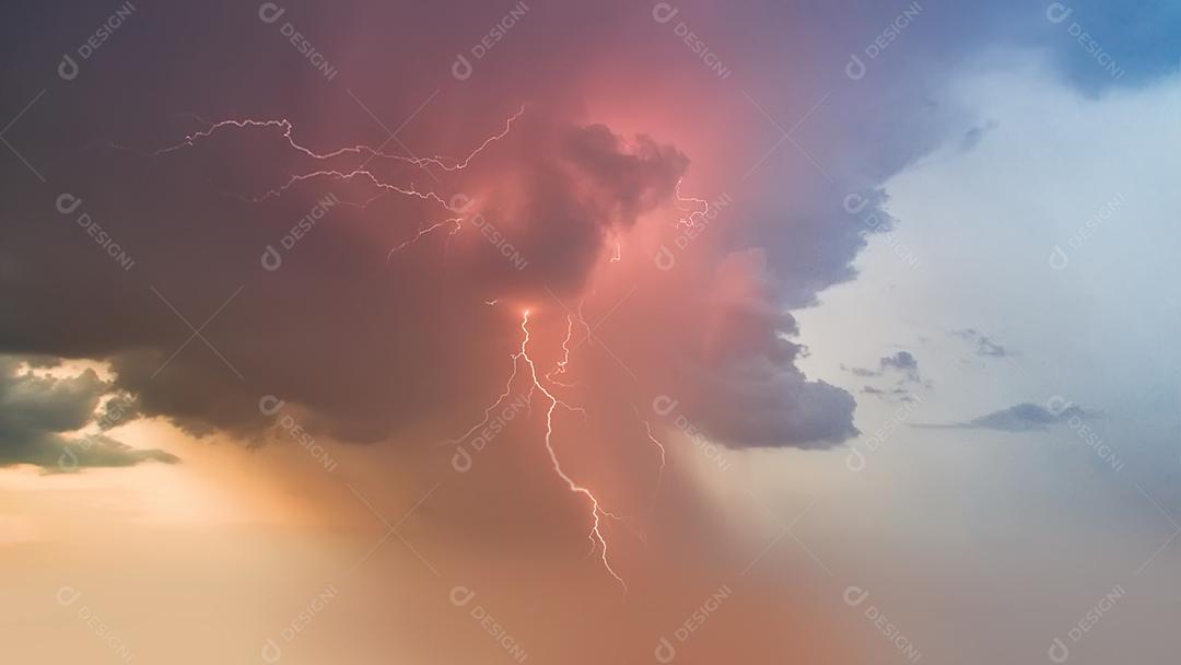 Ceu com nuvens coloridas pelo por do sol e com raios de chuva