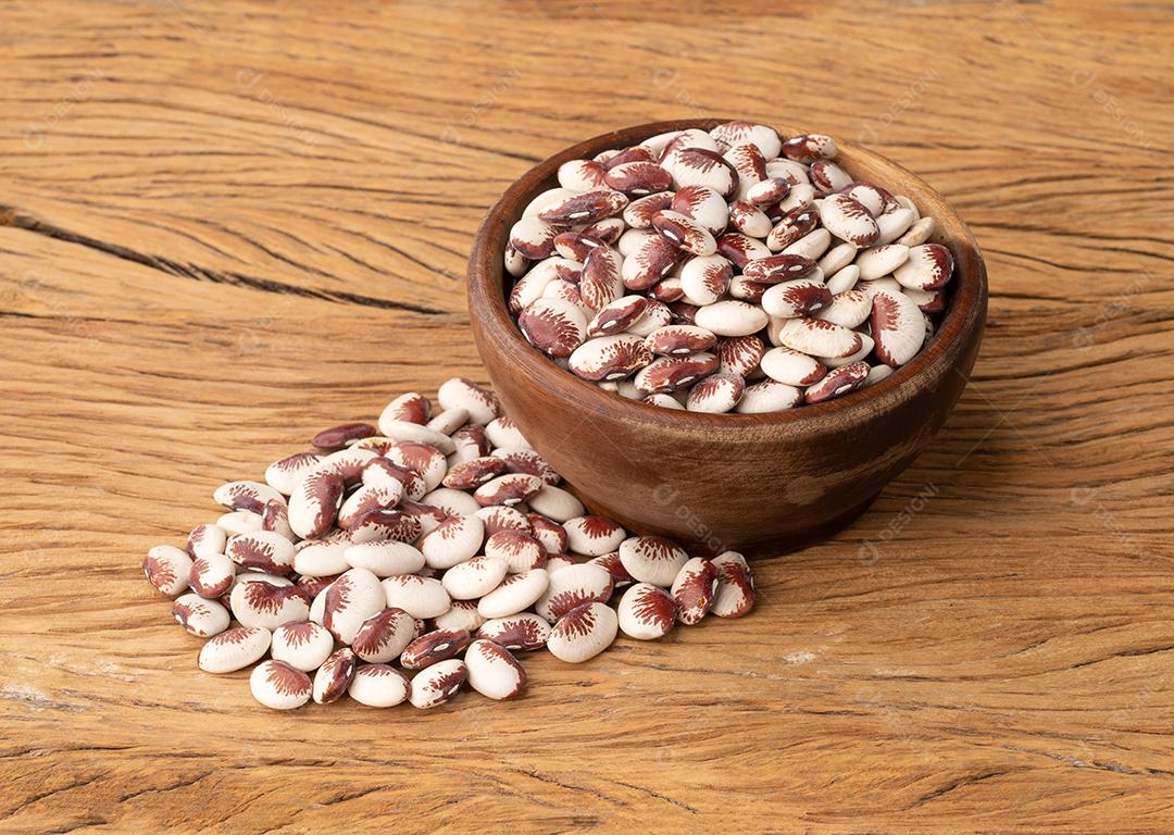 Feijão rajado vermelho em uma tigela sobre mesa de madeira