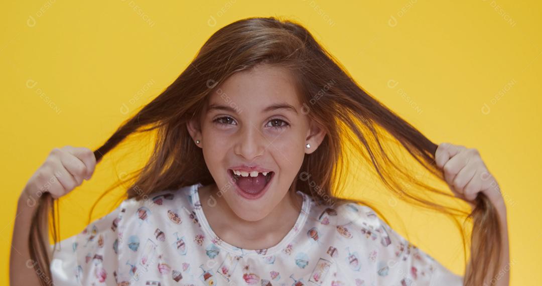 Criança feliz chupando pirulito em fundo amarelo