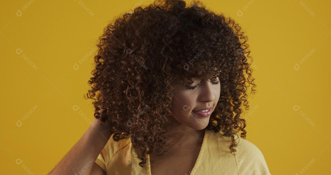 Feliz rindo mulher africana americana com seu cabelo encaracolado em fundo amarelo. Rindo mulher encaracolada