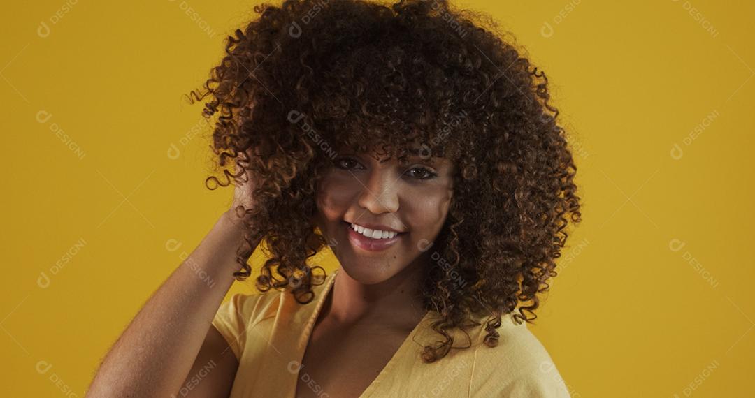 Feliz rindo mulher africana americana com seu cabelo encaracolado em fundo amarelo. Rindo mulher encaracolada