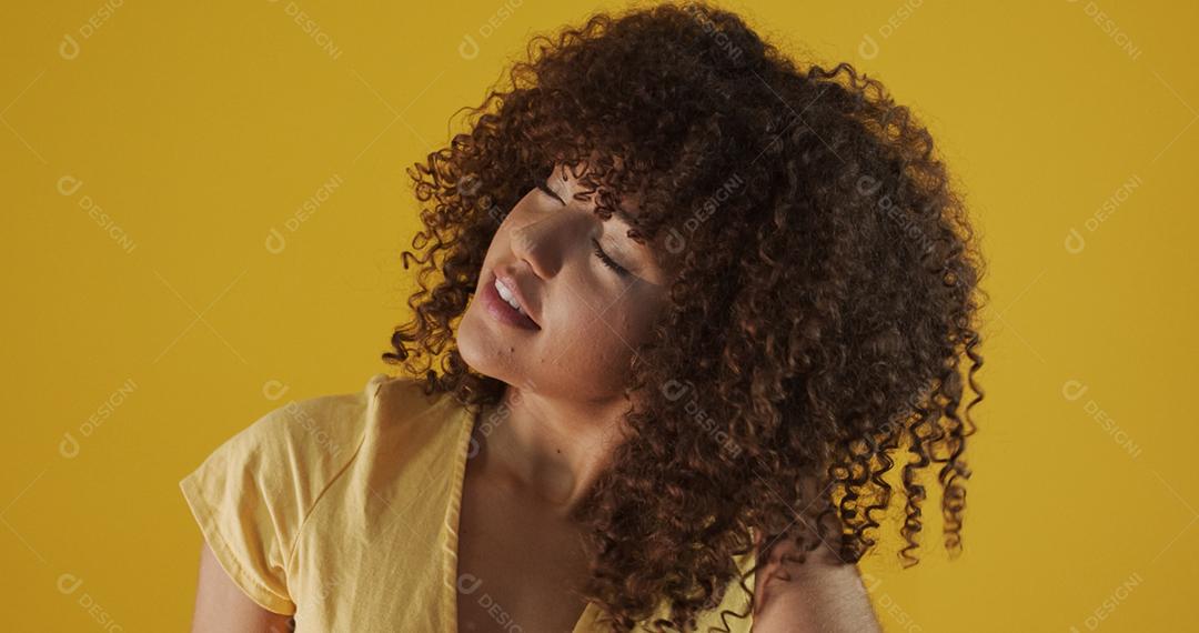 Feliz rindo mulher africana americana com seu cabelo encaracolado em fundo amarelo. Rindo mulher encaracolada