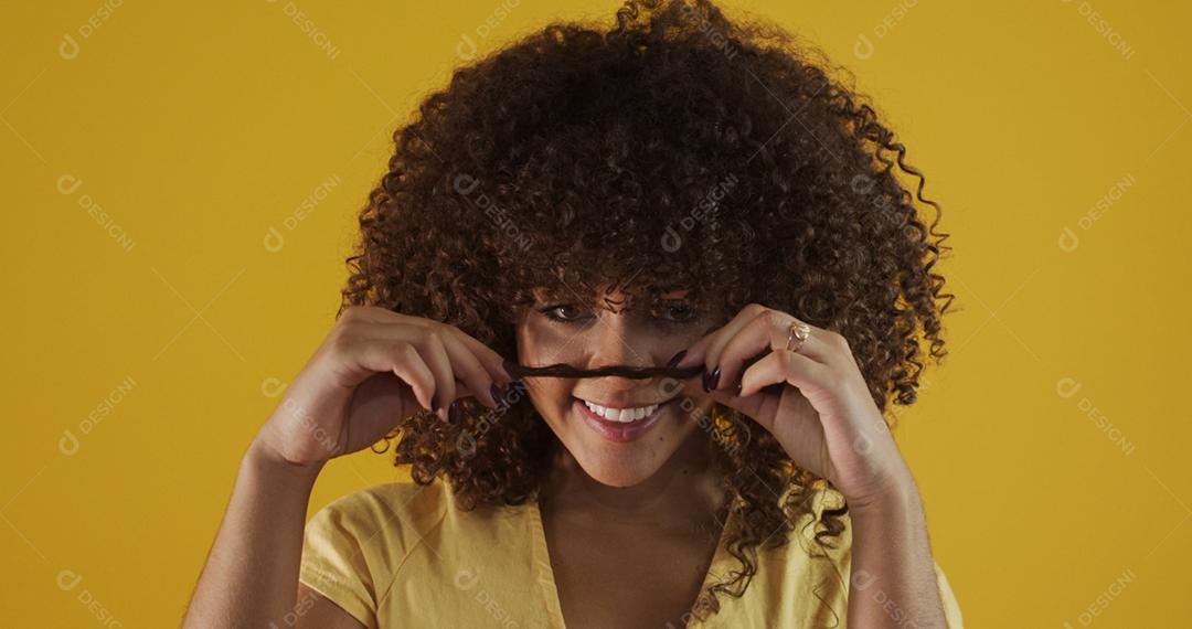 Feliz rindo mulher africana americana com seu cabelo encaracolado em fundo amarelo. Rindo mulher encaracolada