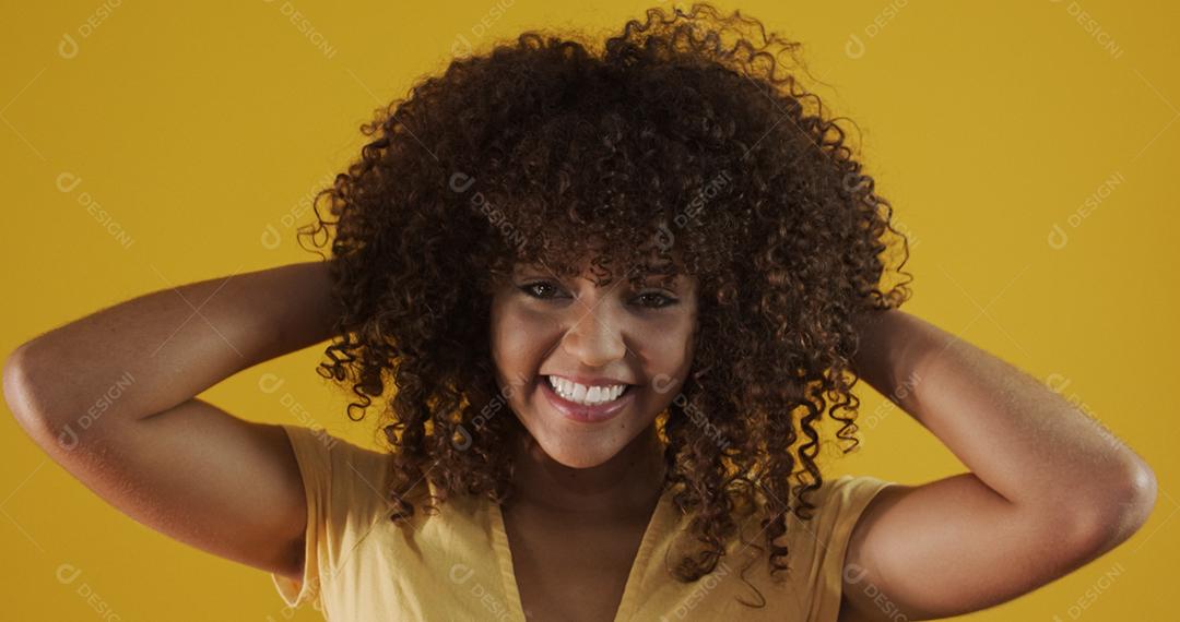 Feliz rindo mulher africana americana com seu cabelo encaracolado em fundo amarelo. Rindo mulher encaracolada