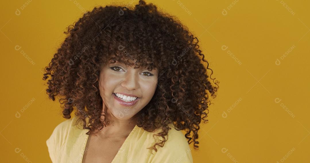 Feliz rindo mulher africana americana com seu cabelo encaracolado em fundo amarelo. Rindo mulher encaracolada