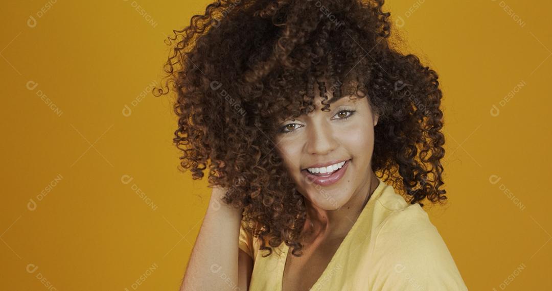 Feliz rindo mulher africana americana com seu cabelo encaracolado em fundo amarelo. Rindo mulher encaracolada