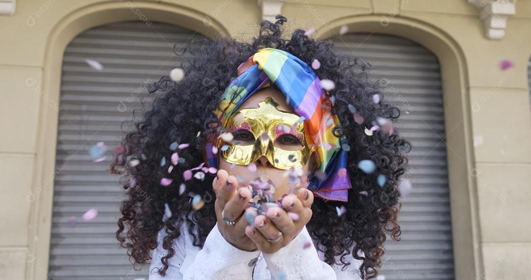 festa carnavalesca. Mulher brasileira de cabelo encaracolado fantasiada soprando confetes.