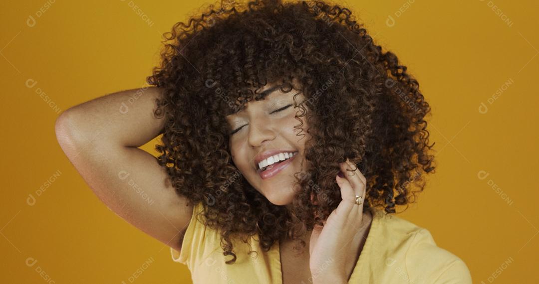 Feliz rindo mulher africana americana com seu cabelo encaracolado em fundo amarelo. Rindo mulher encaracolada .