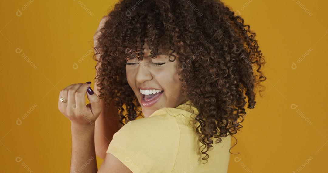 Feliz rindo mulher africana americana com seu cabelo encaracolado em fundo amarelo. Rindo mulher encaracolada .