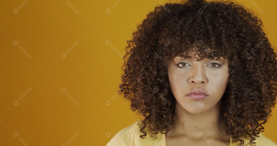 Bela modelo morena séria em amarelo. Cabelo encaracolado. jovem brasileira.