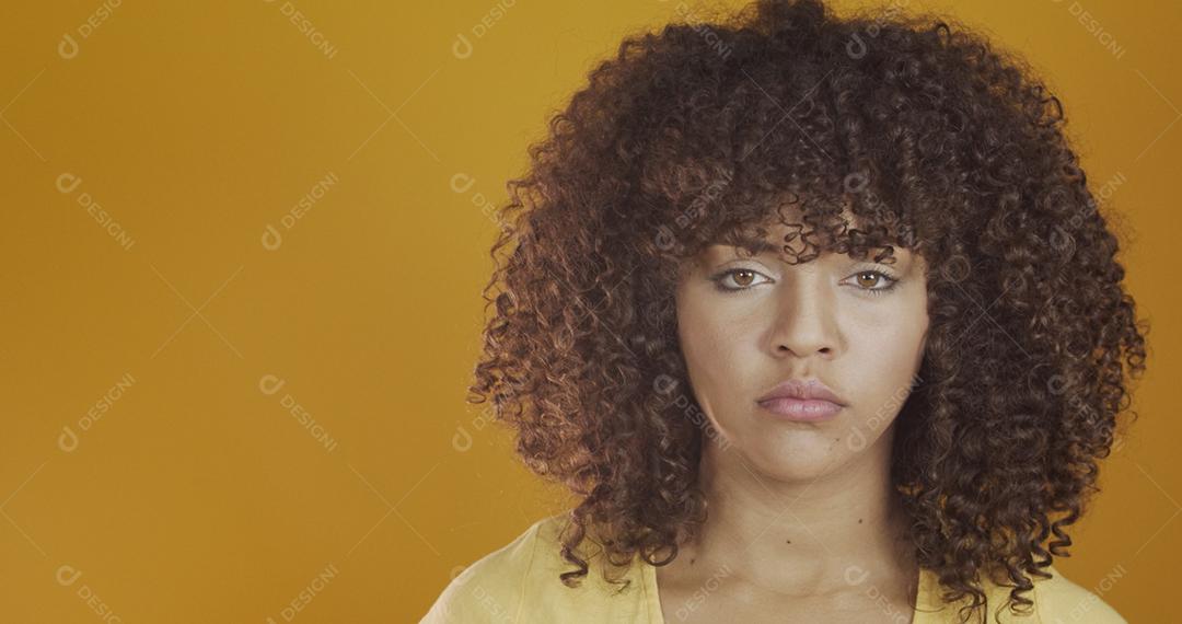 Bela modelo morena séria em amarelo. Cabelo encaracolado. jovem brasileira.