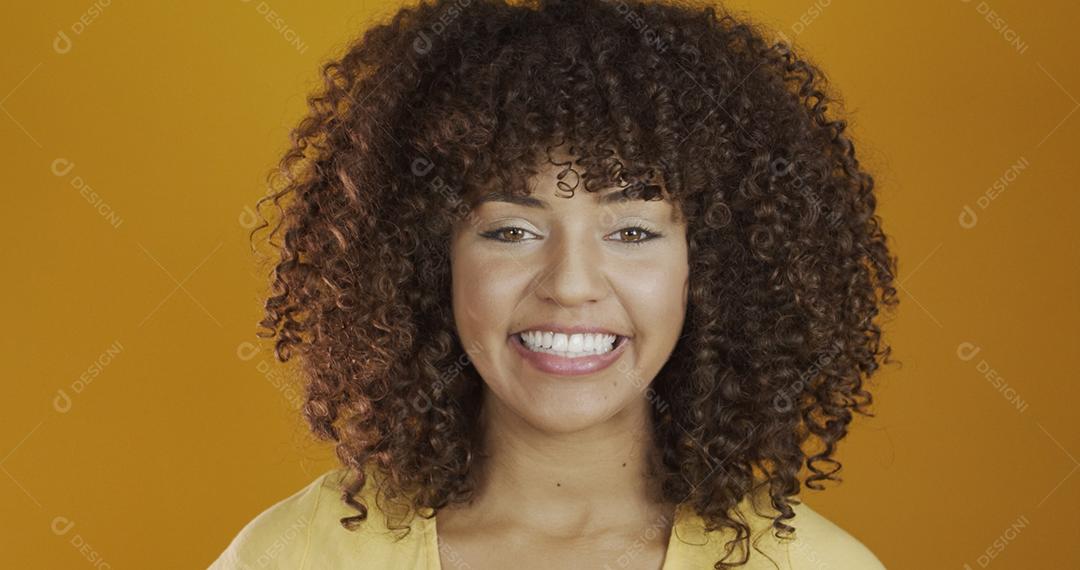 Bela modelo morena séria em amarelo. Cabelo encaracolado. jovem brasileira.