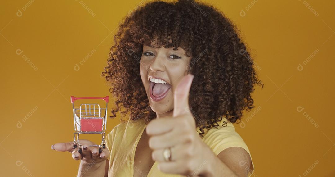 Menina com pequeno cartão de compras. Sorrindo e dançando mulher de cabelo encaracolado no conceito de compras