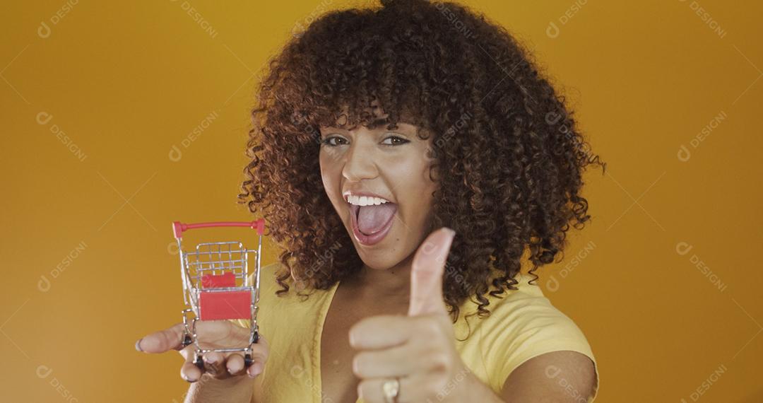 Menina com pequeno cartão de compras. Sorrindo e dançando mulher de cabelo encaracolado no conceito de compras