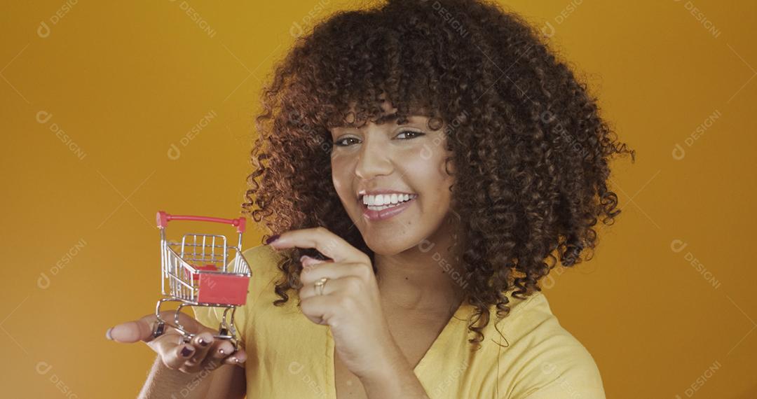 Menina com pequeno cartão de compras. Sorrindo e dançando mulher de cabelo encaracolado no conceito de compras