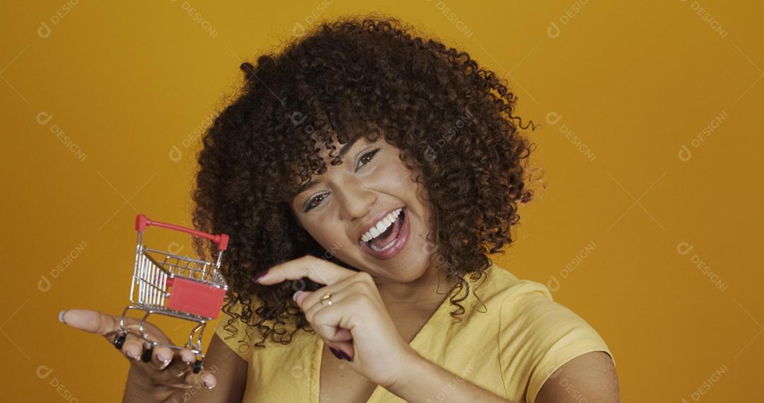 Menina com pequeno cartão de compras. Sorrindo e dançando mulher de cabelo encaracolado no conceito de compras