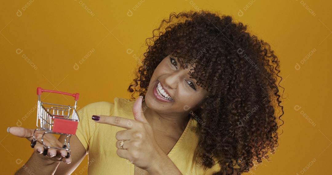 Menina com pequeno cartão de compras. Sorrindo e dançando mulher de cabelo encaracolado no conceito de compras