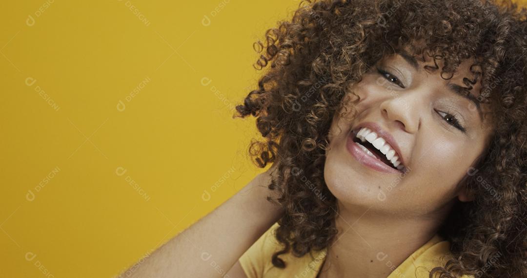 Feliz rindo mulher africana americana com seu cabelo encaracolado em fundo amarelo. Rindo mulher encaracolada