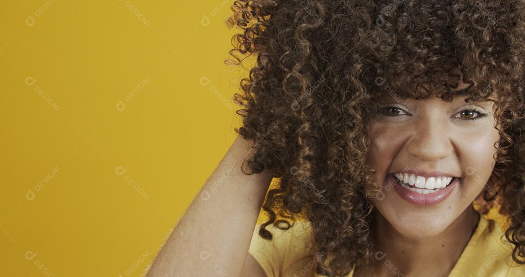 Feliz rindo mulher africana americana com seu cabelo encaracolado em fundo amarelo. Rindo mulher encaracolada