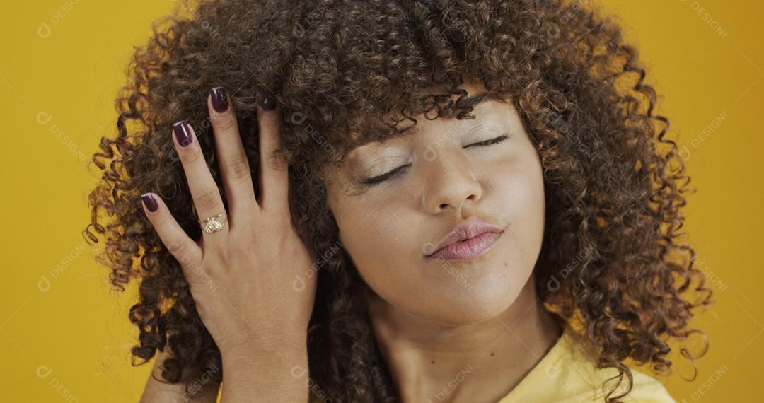 Feliz rindo mulher africana americana com seu cabelo encaracolado em fundo amarelo. Rindo mulher encaracolada