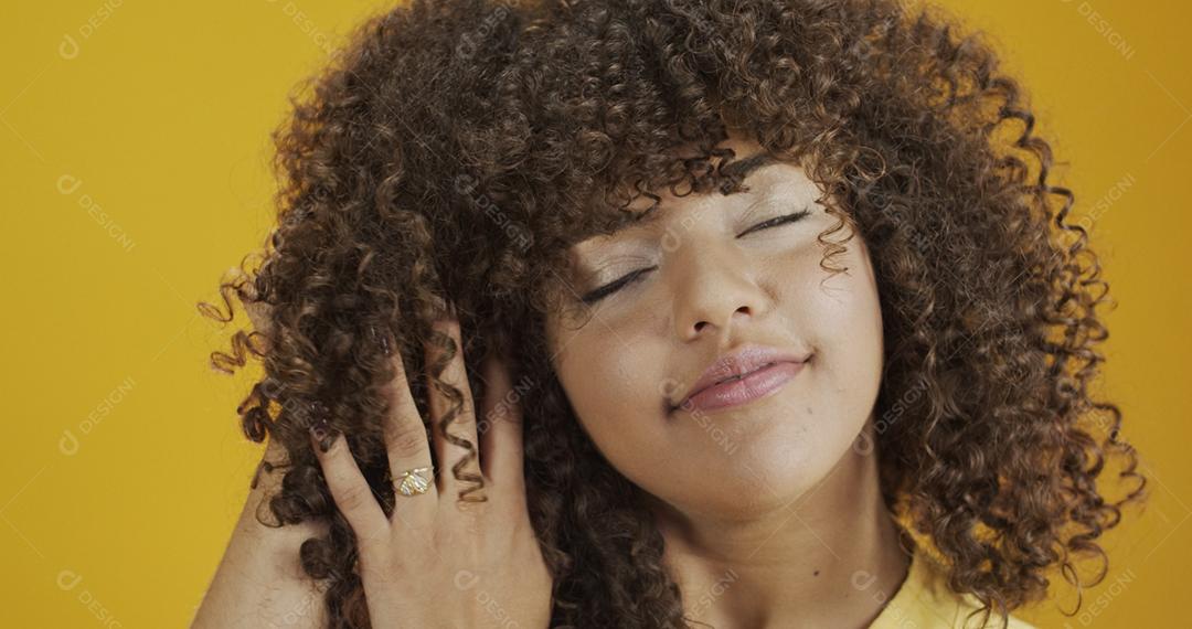 Feliz rindo mulher africana americana com seu cabelo encaracolado em fundo amarelo. Rindo mulher encaracolada