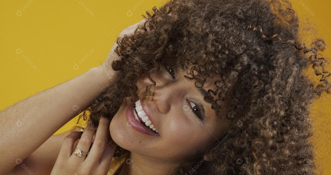 Feliz rindo mulher africana americana com seu cabelo encaracolado em fundo amarelo. Rindo mulher encaracolada