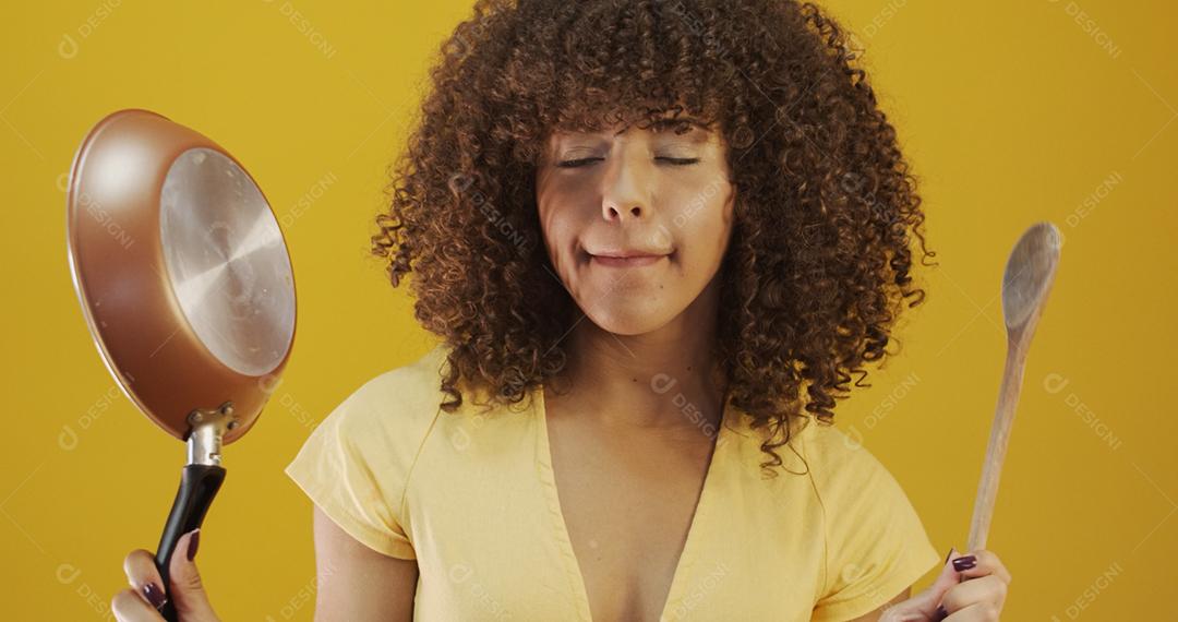 Utensílios de cozinha. Cozinhar a mulher na cozinha com frigideira e colher de pau. Dona de casa dançando.