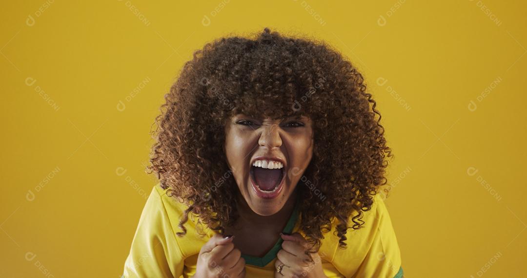 Torcedor do Brasil. Fã de mulher brasileira de cabelo encaracolado comemorando no futebol, partida de futebol