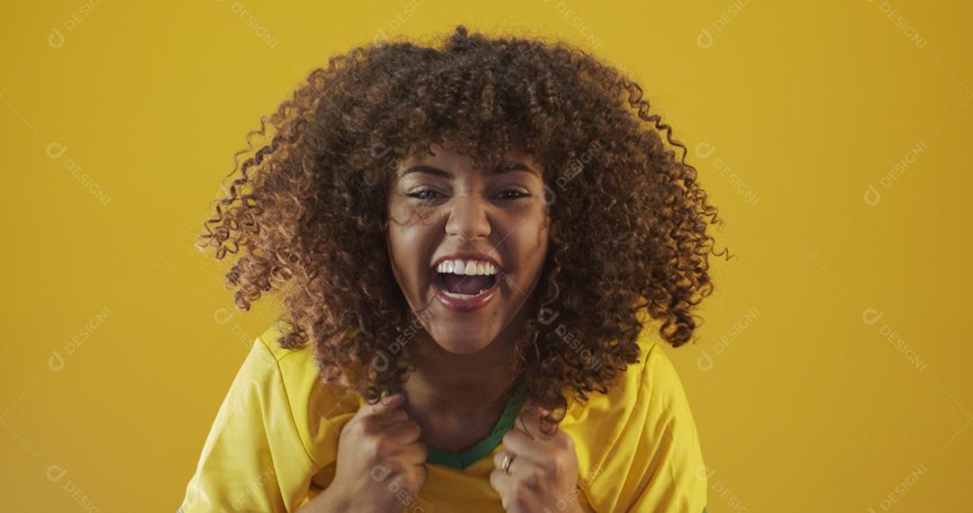 Torcedor do Brasil. Fã de mulher brasileira de cabelo encaracolado comemorando no futebol, partida de futebol