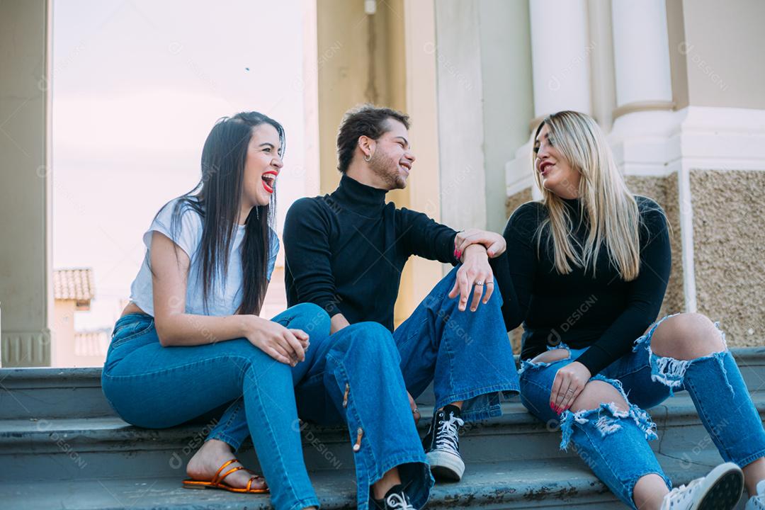 Grupo de amigos latinos sorridentes sentados na rua da cidade. Conceito de verão e pessoas.